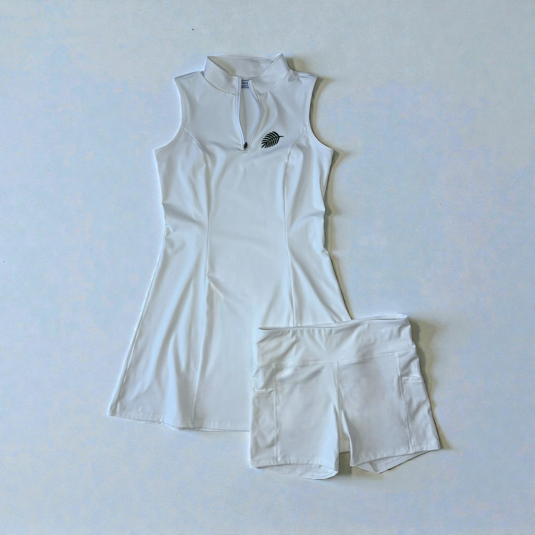 White sleeveless athletic top and shorts set on a light blue background