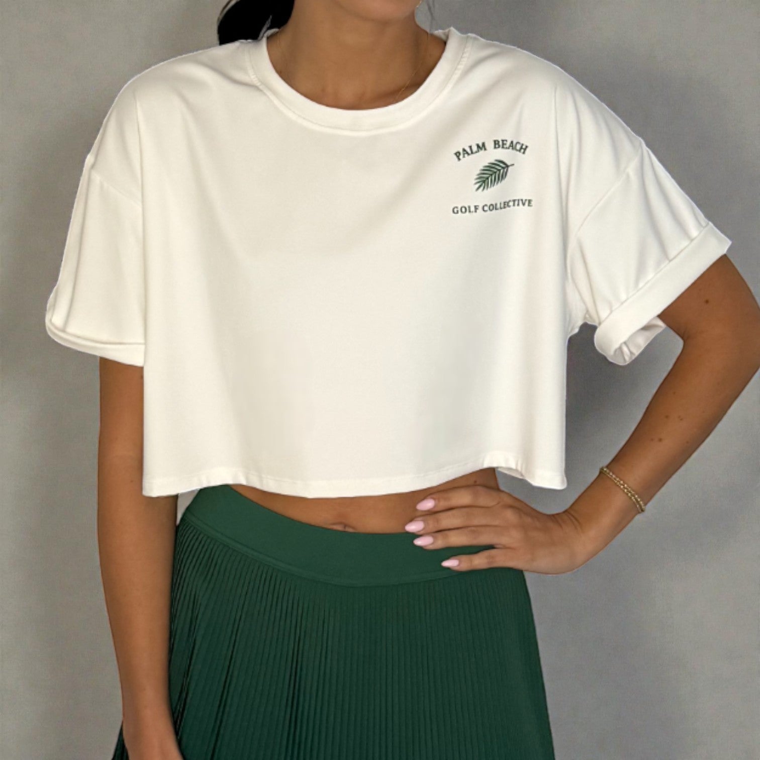 Person wearing a white t-shirt with a logo and green skirt on a gray background