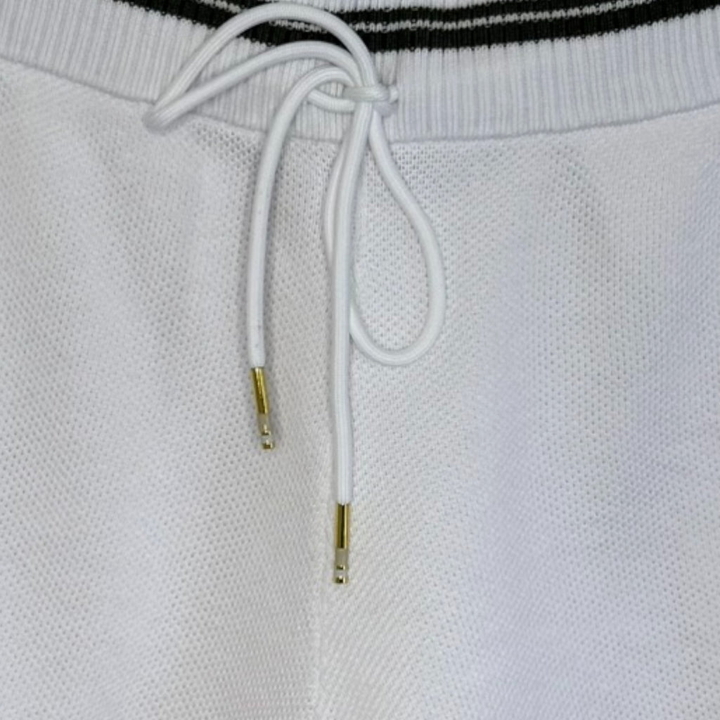 Close-up of white drawstring with gold metal tags on a white background