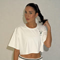 Woman wearing a white t-shirt with a logo against a plain background