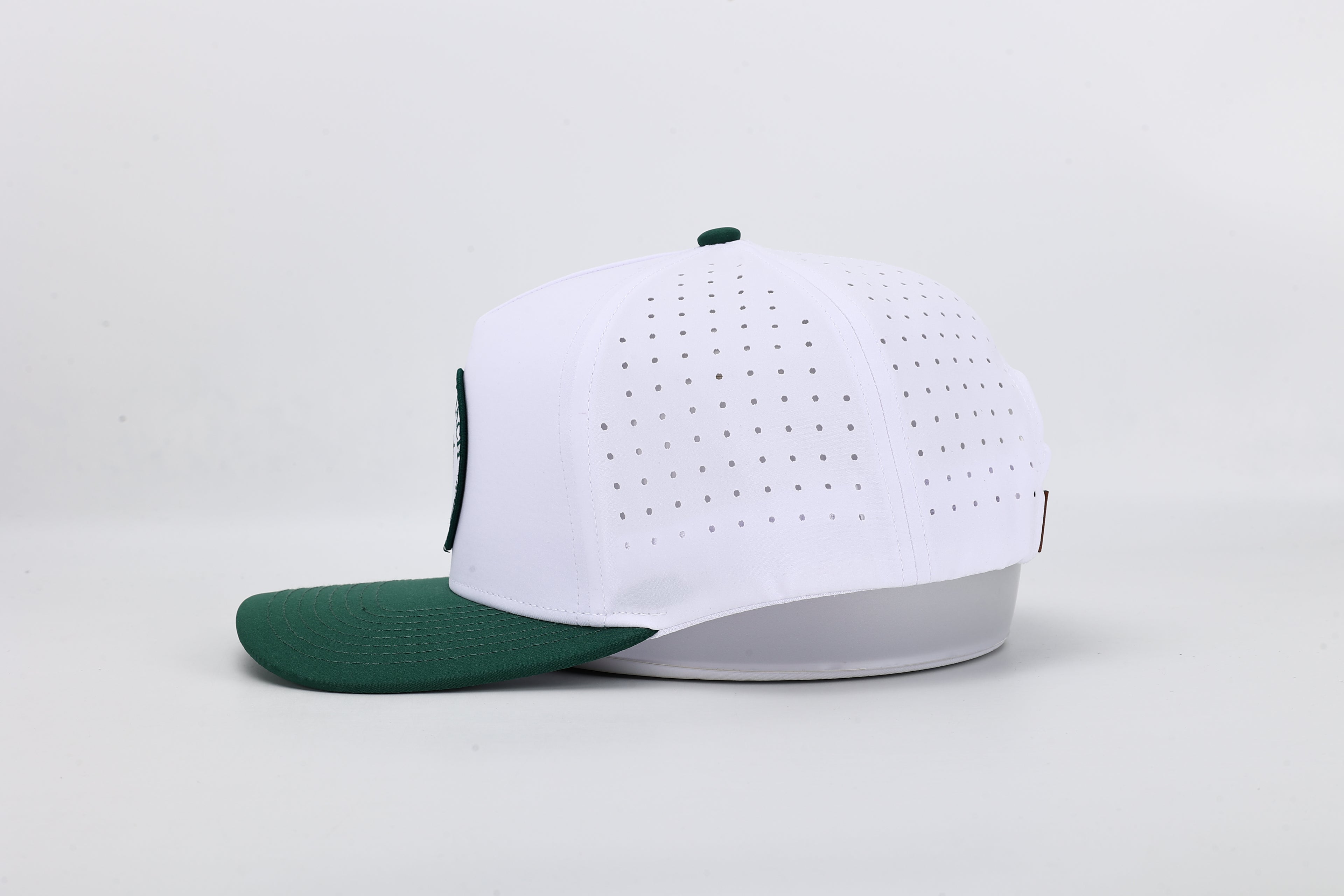 White baseball cap with green brim on a light gray background