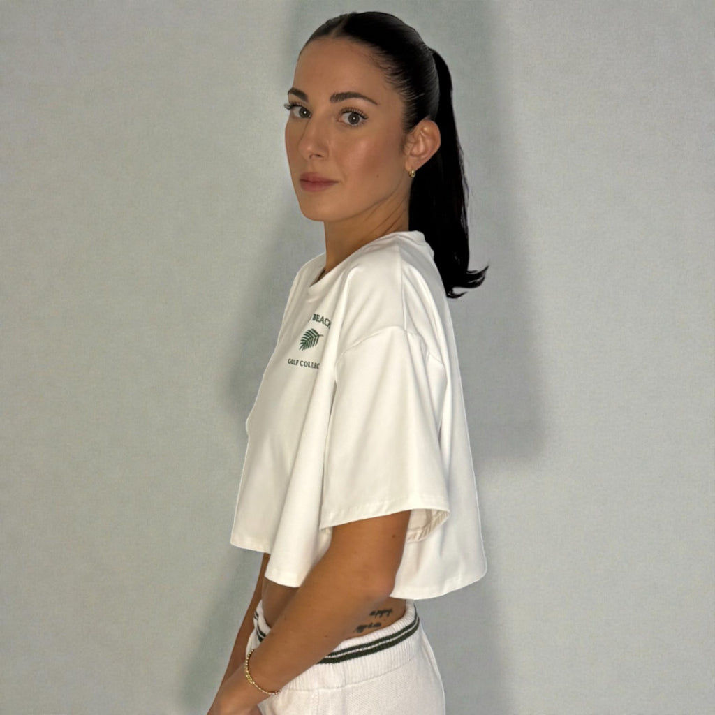 Woman wearing a white t-shirt with a logo against a plain background