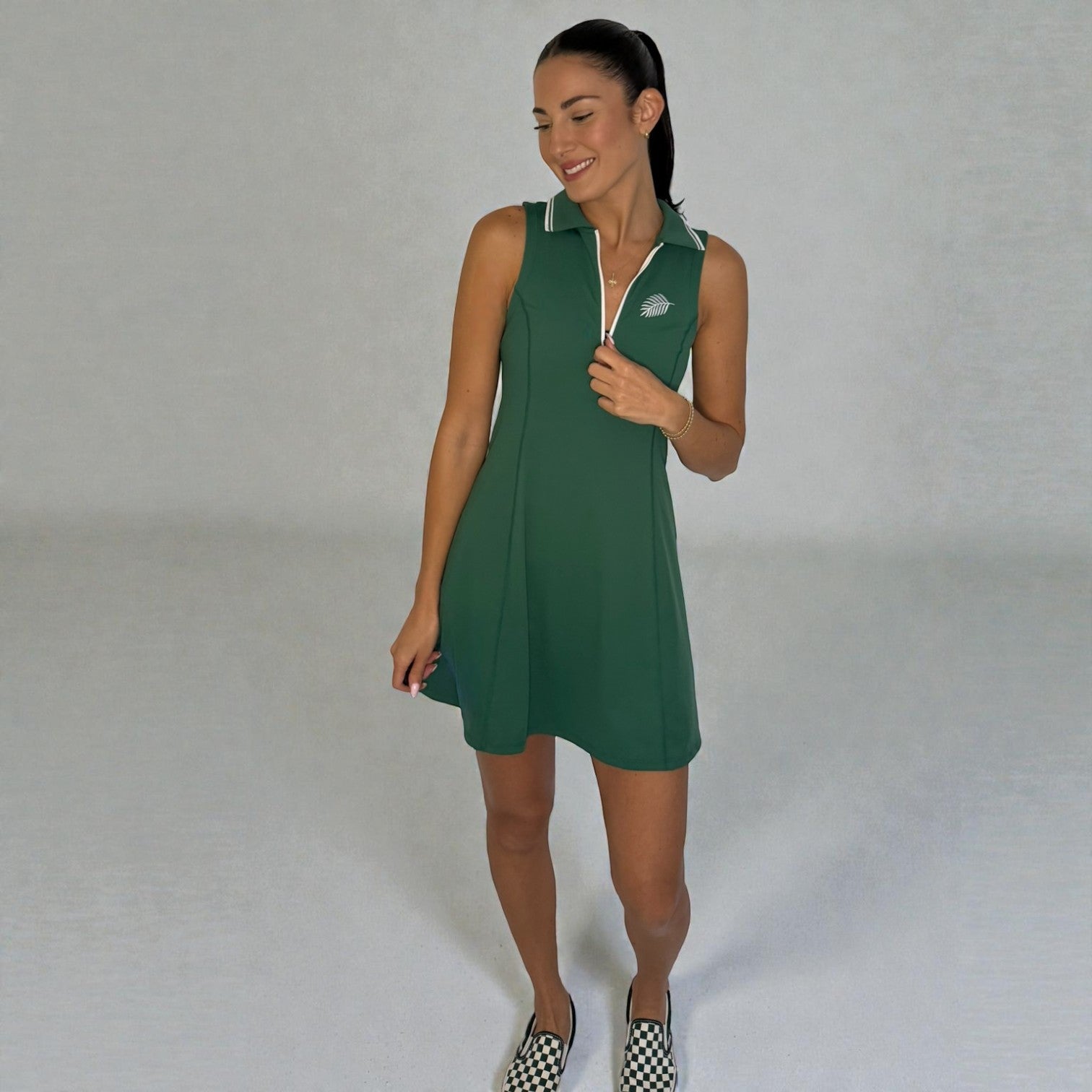 Woman wearing a green dress with a white collar against a plain background