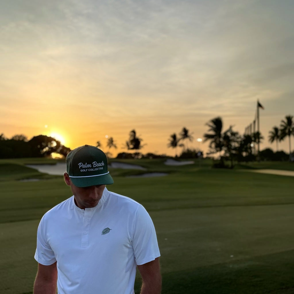 PBGC deep green golf rope hat with white embroidery worn by a man on a golf course at sunset