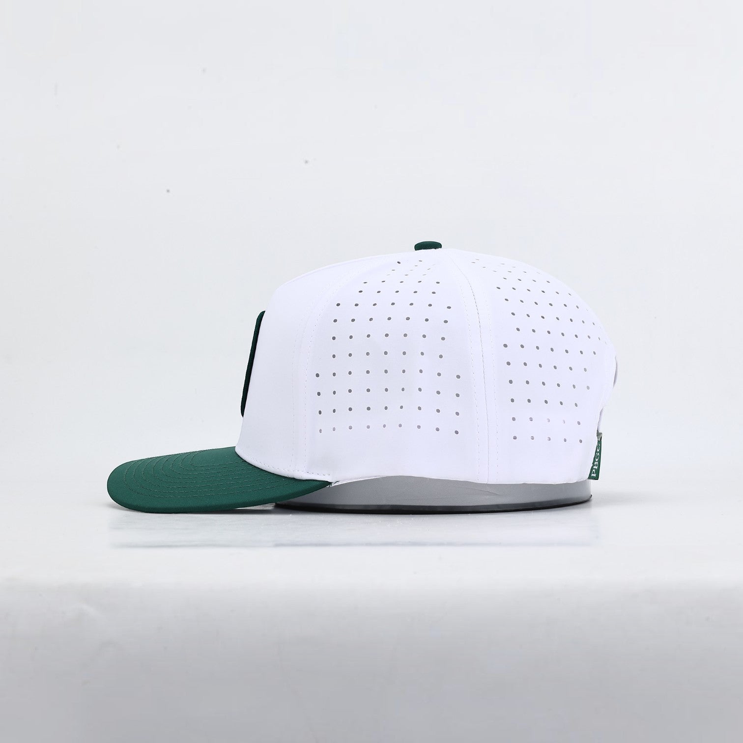 PBGC The Palm Patch Hat featuring a white perforated crown and deep green bill in a side profile view.