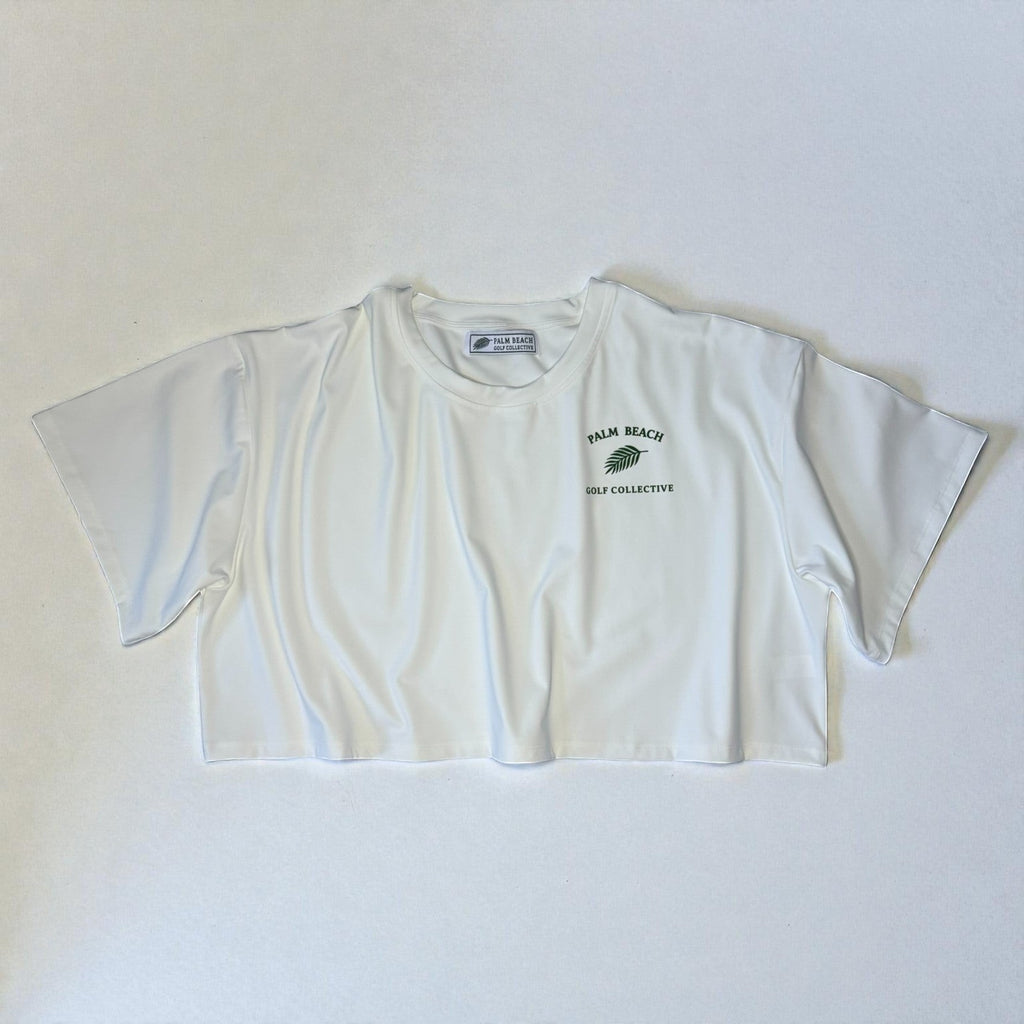 PBGC white crop top with a relaxed boxy fit, crew neckline, and green Palm Beach Golf Collective chest logo.