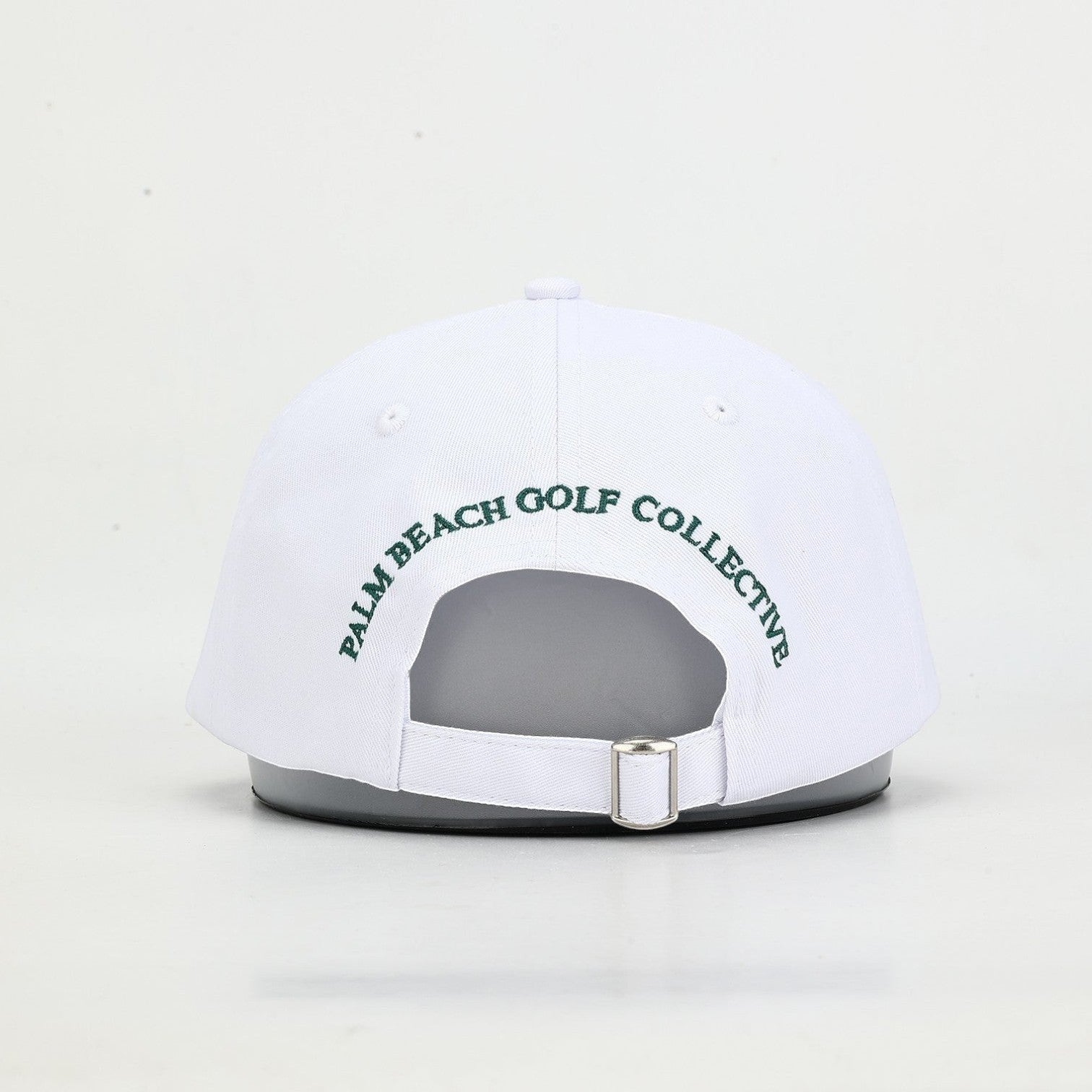 PBGC white cotton twill baseball cap with green embroidered text on the back and an adjustable metal strap