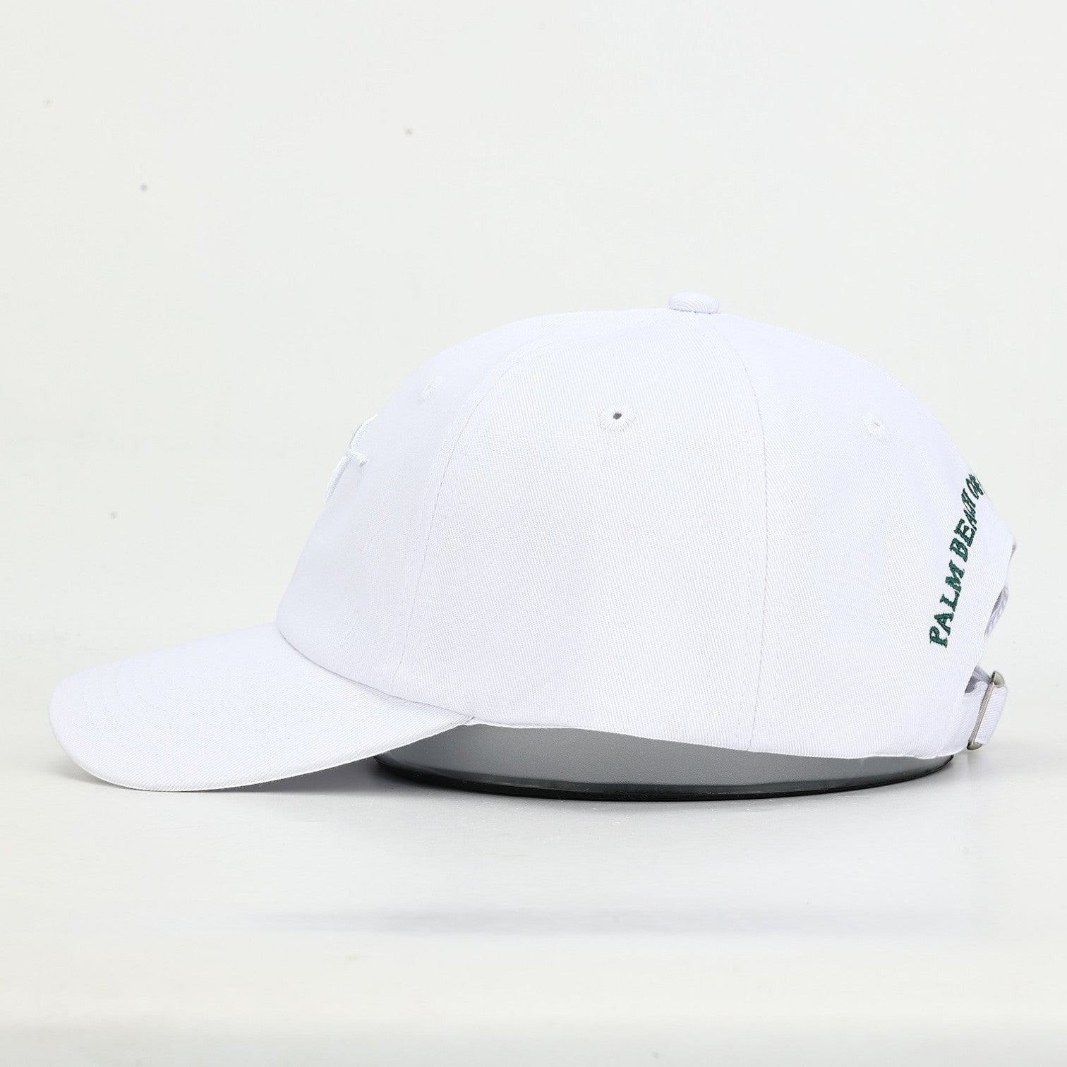 PBGC white cotton twill baseball cap with side green embroidery and adjustable strap, side profile view.