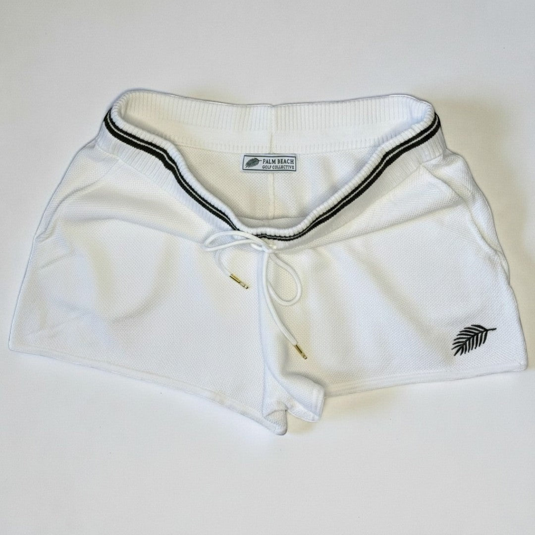 PBGC white cotton knit shorts with dark green striped waistband, drawstring closure, and palm leaf embroidery.