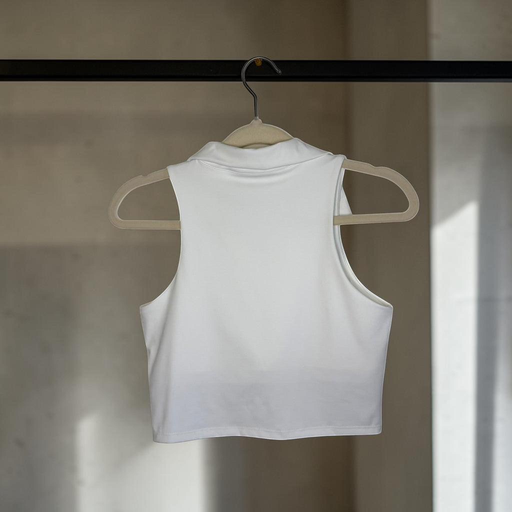 PBGC white cropped sleeveless golf polo tank top with a soft collar hanging on a hanger