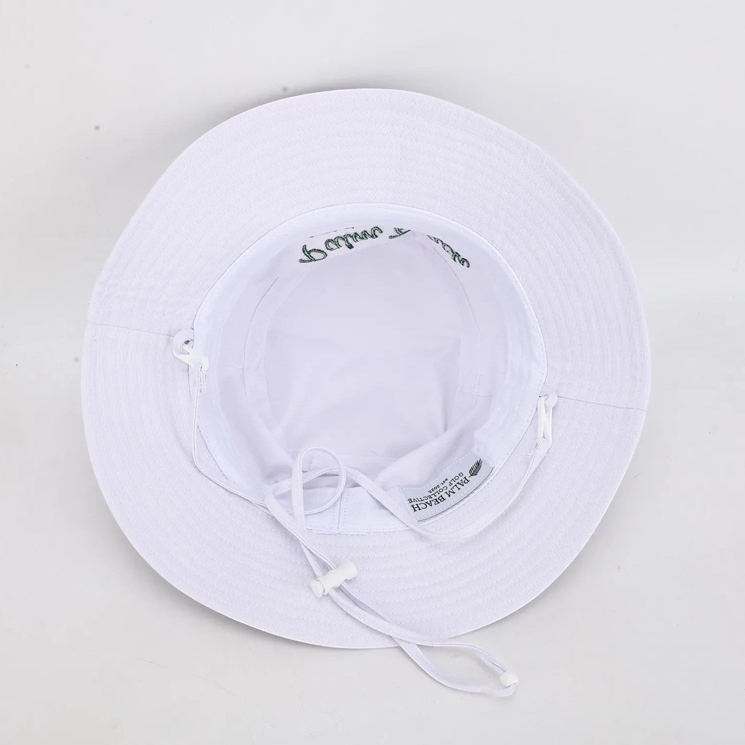 PBGC white bucket hat with adjustable chin strap and green embroidery, viewed from the inside.