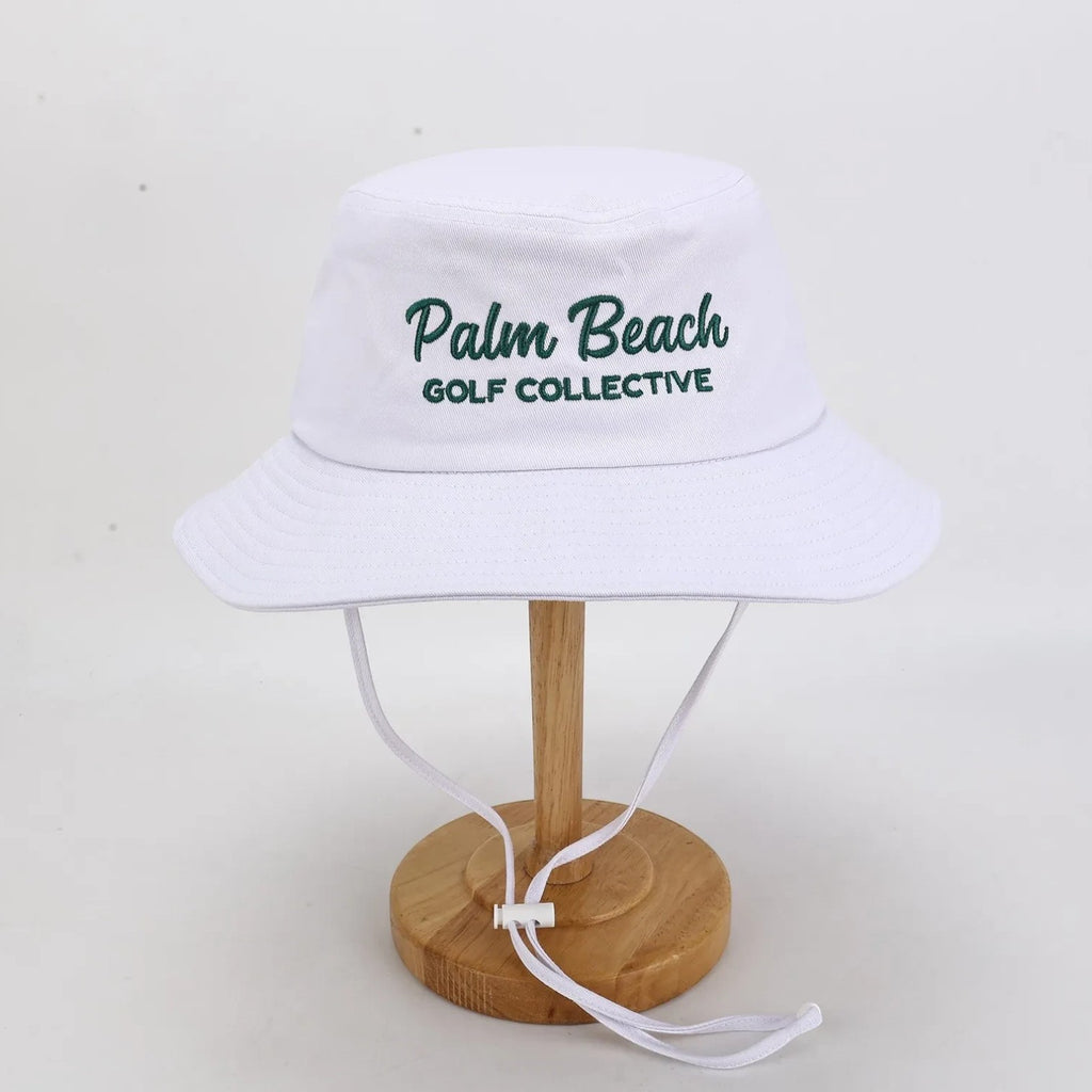 PBGC white bucket hat with green Palm Beach Golf Collective embroidery and adjustable chin strap for golf.