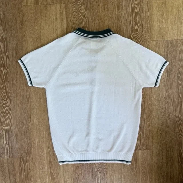 PBGC white knit polo shirt with olive green striped collar and cuffs, back view showing raglan sleeves