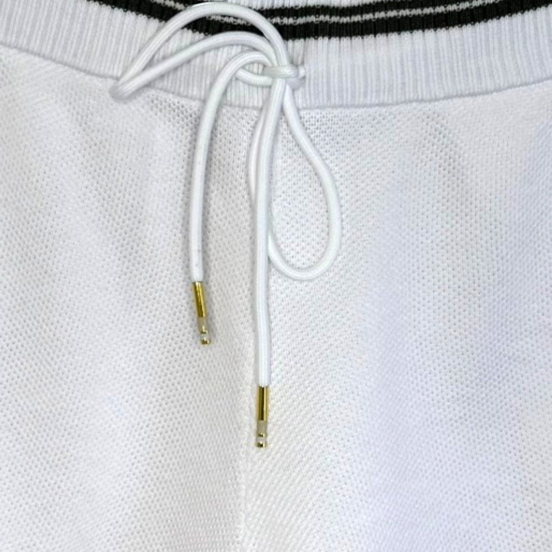PBGC white cotton knit shorts featuring a dark green striped waistband and white drawstring with gold aglets.