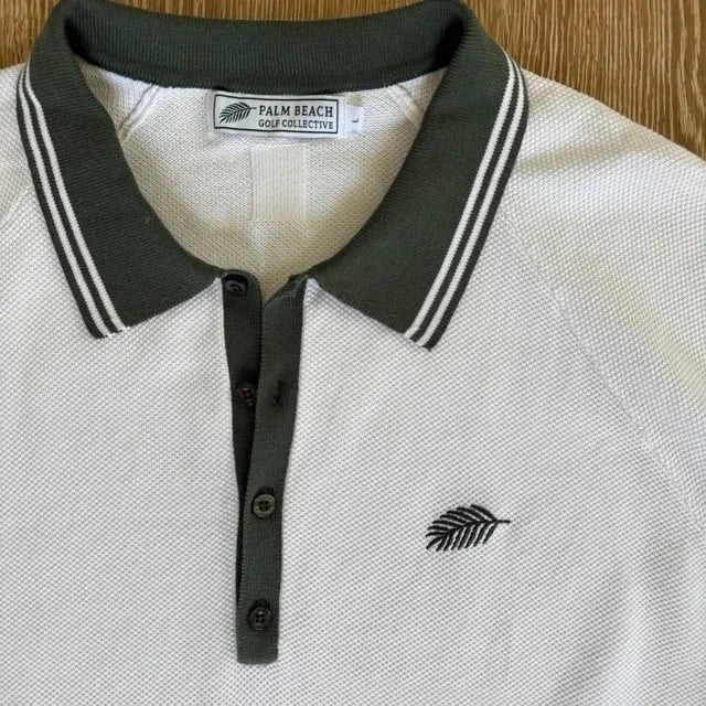 PBGC white knit golf polo with olive green striped collar, placket, and signature palm leaf chest embroidery.