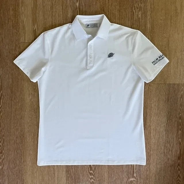 PBGC white performance golf polo with a palm leaf logo on the chest and signature branding on the sleeve.