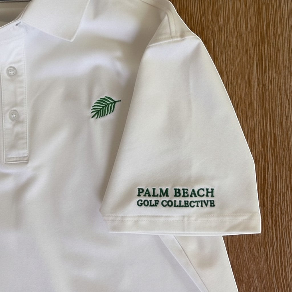 PBGC white performance golf polo with green palm leaf chest logo and sleeve branding