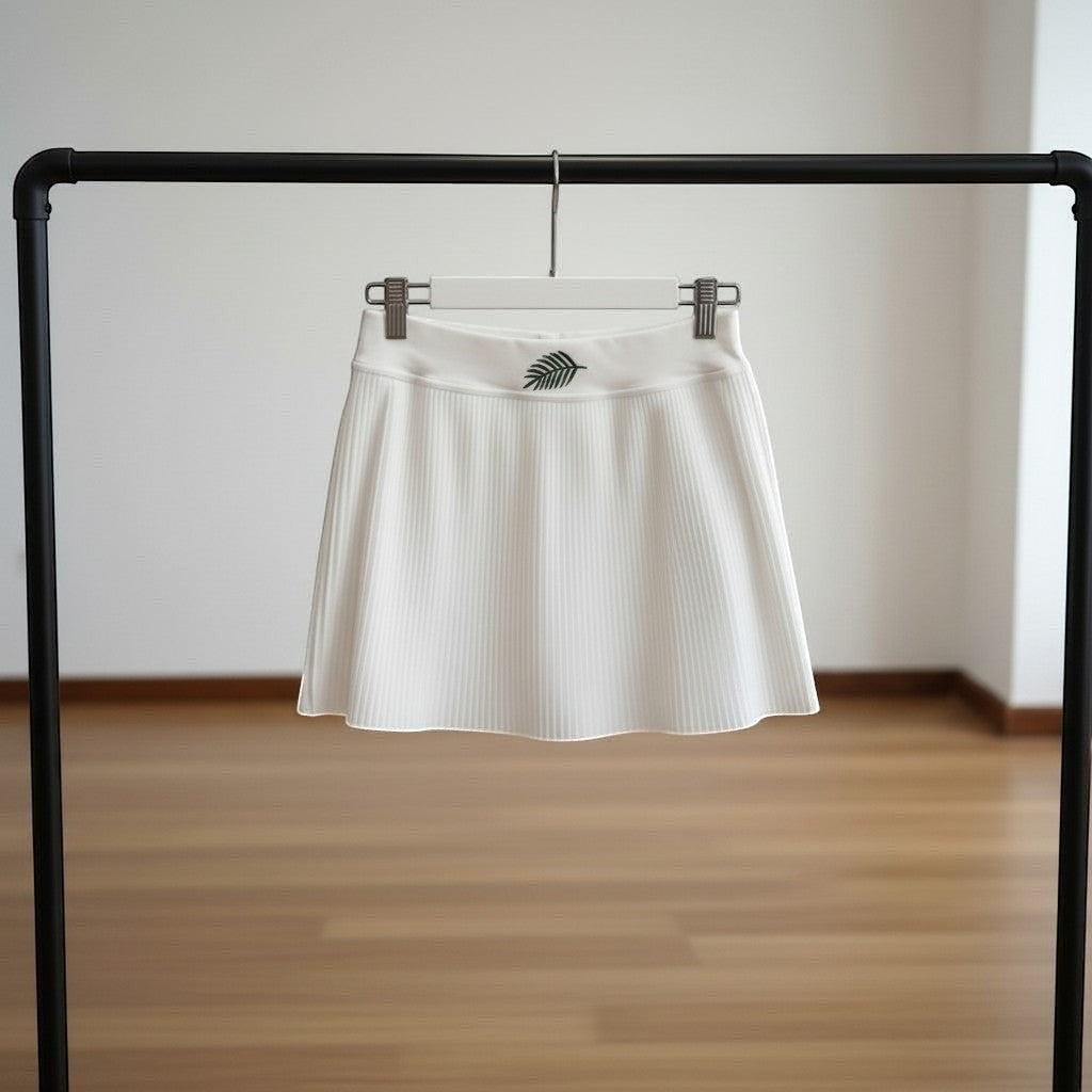 PBGC white pleated athletic skort with built-in shorts and a small green leaf embroidery on the high waistband.