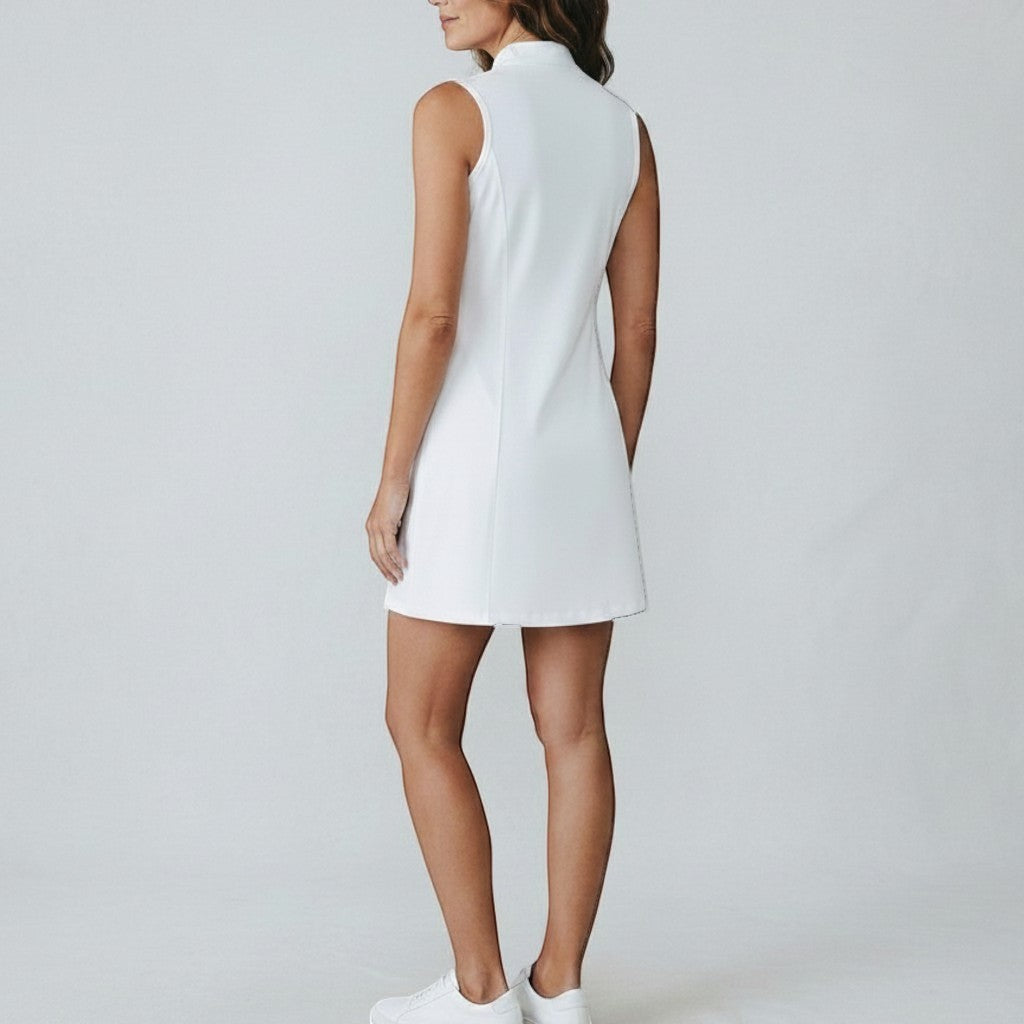 Back view of a woman wearing a white PBGC sleeveless performance golf dress with a mock-neck collar.